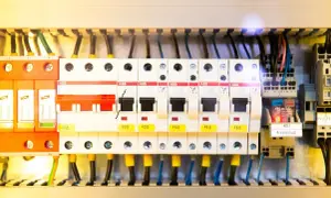Wnętrze rozdzielni elektrycznej z widocznymi zabezpieczeniami, przewodami i elementami sterującymi.