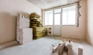 Materiały do ocieplania ścian od wewnątrz styropianem: białe bloczki, żółta wełna mineralna, narzędzia budowlane.