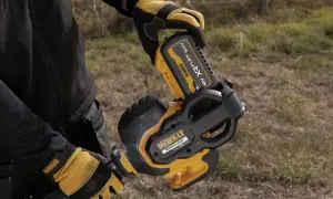 Ręce w rękawicach DeWalt montują akumulator 54V do narzędzia. DeWalt to znana firma produkująca elektronarzędzia.