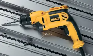 Żółto-czarna wiertarka dwubiegowa bez udaru DeWalt wierci w metalowym profilu, pozostawiając wióry.
