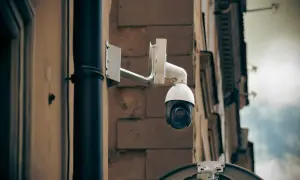 Kamera monitoringu na ścianie budynku, gotowa do zarejestrowania każdego zdarzenia, stanowiąc dowód kradzieży.