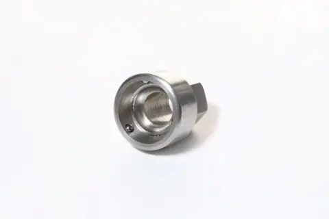 Metalowy, sześciokątny element z otworem w środku, z widoczną kulką wewnątrz. To uniwersalny klucz do śrub zabezpieczających.