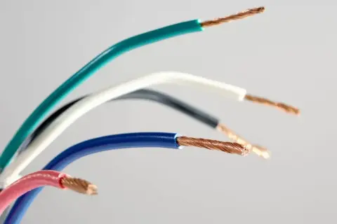 Kolorowy przewód elektryczny, z odsłoniętymi miedzianymi żyłkami. Widoczne izolacje w kolorach: zielonym, białym, czarnym, niebieskim i różowym.
