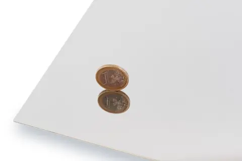 Błyszcząca powierzchnia, efekt polerowania stali nierdzewnej, odbija monetę euro.