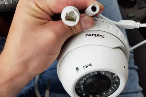 Dłoń trzyma białą kamerę IP z logo "fortec for vision". Widać złącze RJ45 i zasilania. Dowiedz się, jak podłączyć kamerę bez rejestratora.