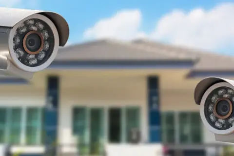 Dwie kamery monitoringu wizyjnego przed domem, zapewniające domowy monitoring.