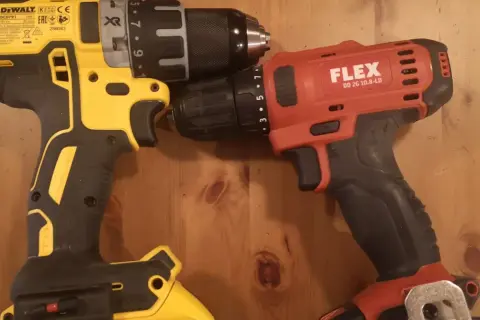 Dwie wkrętarki: żółto-czarna DeWalt i czerwono-czarna Flex, leżą obok siebie na drewnianym blacie.
