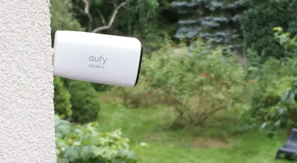 Kamera Eufy Security zapewnia monitoring działki przez internet mobilny. Widok ogrodu z kamerą zamontowaną na ścianie.