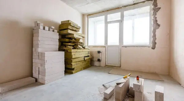 Materiały do ocieplania ścian od wewnątrz styropianem: białe bloczki, żółta wełna mineralna, narzędzia budowlane.