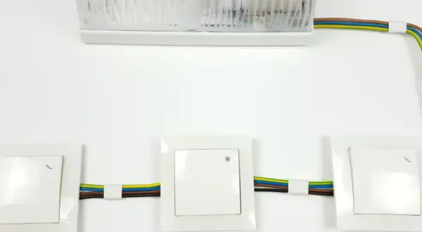 Schemat instalacji elektrycznej: jak podłączyć łącznik krzyżowy. Widoczne trzy łączniki i lampa.
