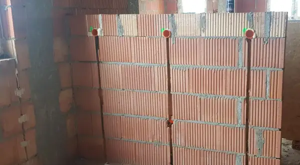 Przygotowanie ścian do instalacji elektrycznej: widoczne bruzdowanie pod kable w ceglanej ścianie, z widocznymi puszkami instalacyjnymi.