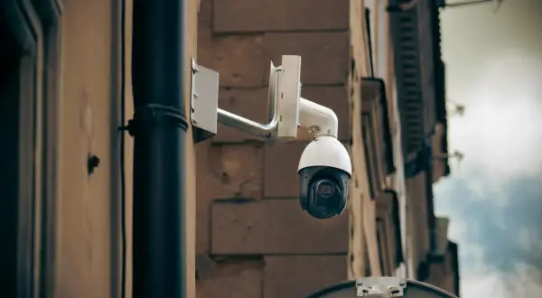 Kamera monitoringu na ścianie budynku, gotowa do zarejestrowania każdego zdarzenia, stanowiąc dowód kradzieży.