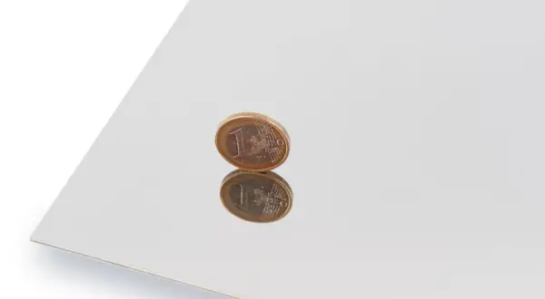 Błyszcząca powierzchnia, efekt polerowania stali nierdzewnej, odbija monetę euro.