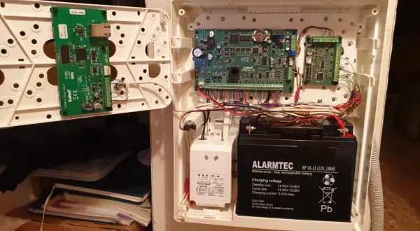 Wnętrze centrali alarmowej Satel z modułem ETHM-1 Plus, płytą główną Integra i akumulatorem.