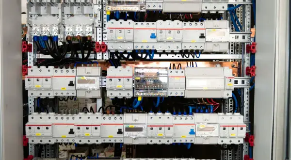 Panel elektryczny z licznymi wyłącznikami i zabezpieczeniami, połączonymi przewodami. Widać tu szyny elektryczne, które stanowią podstawę montażu.