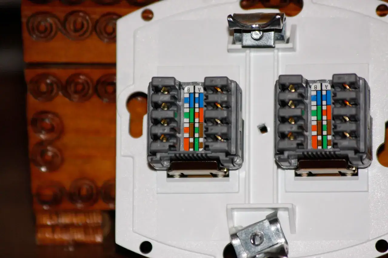 Dwa moduły gniazda RJ-45 z kolorowymi oznaczeniami przewodów, gotowe do podłączenia sieci.