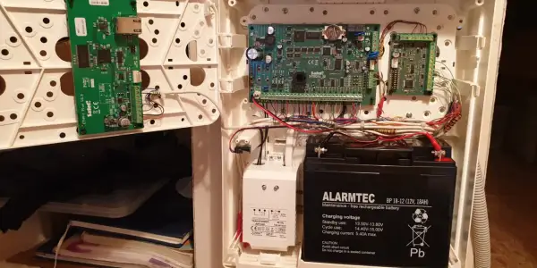Wnętrze obudowy systemu alarmowego satel. Widoczne płyty główne, akumulator i okablowanie.