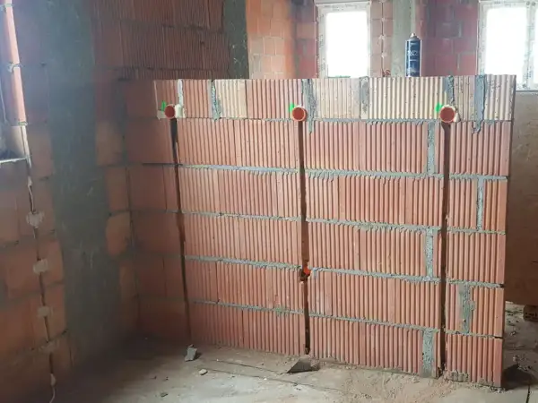 Przygotowanie ścian do instalacji elektrycznej: widoczne bruzdowanie pod kable w ceglanej ścianie, z widocznymi puszkami instalacyjnymi.