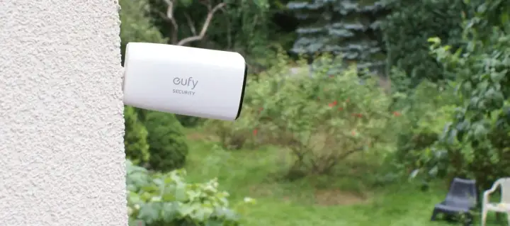 Kamera Eufy Security zapewnia monitoring działki przez internet mobilny. Widok ogrodu z kamerą zamontowaną na ścianie.